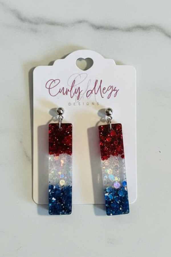 Curly Megs Designs patriotic rectangular glitter bar earrings in red, white, and blue resin.